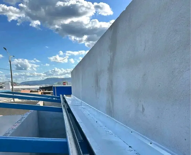Fixação de calha galvanizada em estrutura de telhado com suportes de aço azuis.