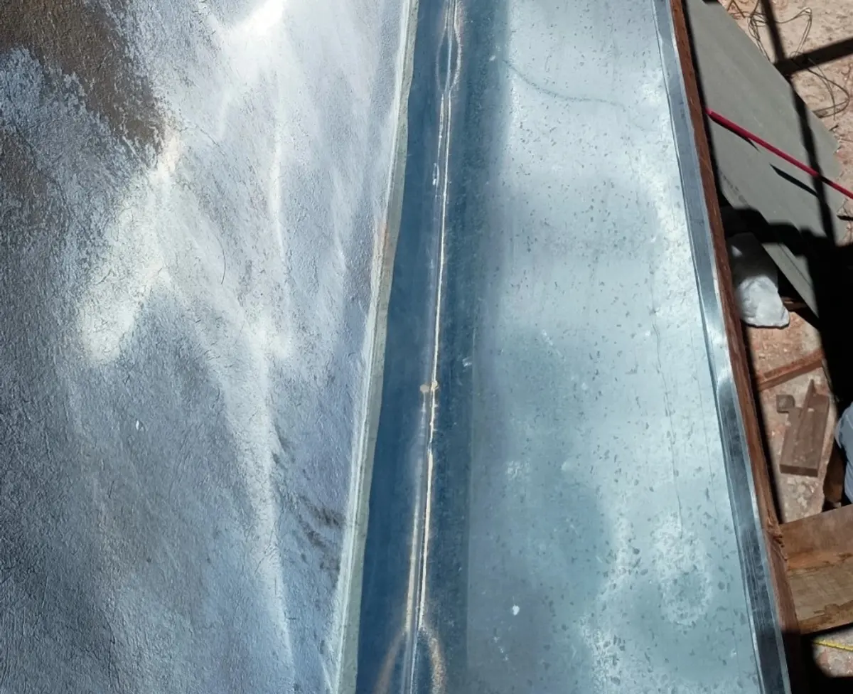 Calha galvanizada instalada em prédio em construção em Petrolina, com o sol refletindo no metal.