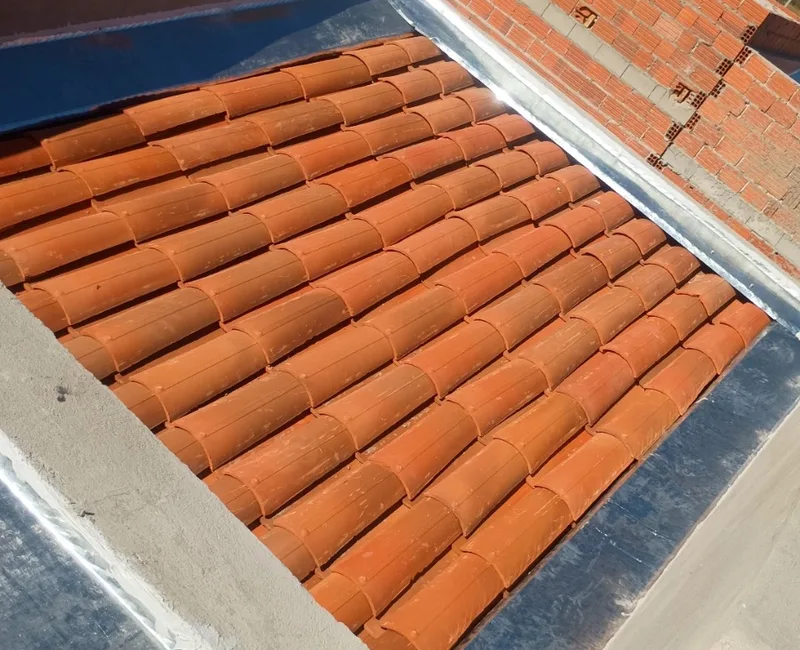 Rufos metálicos instalados sobre telhas cerâmicas sob luz solar intensa.